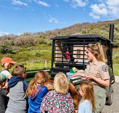 Emma Johnson presenting a bear pelt to young campers, teaching them about black bears. 