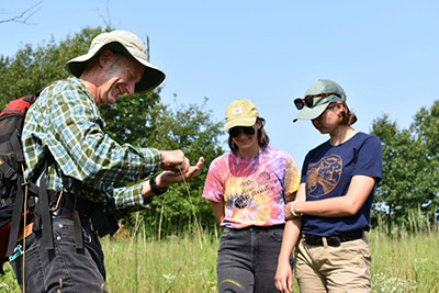 Amber Laughner and her coworker Chloe talk with Doug Botka, ecologist at Shirley Heinze Land Trust, out in the field