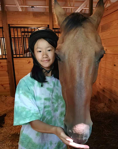 Sophie Low stands next to a horse. 