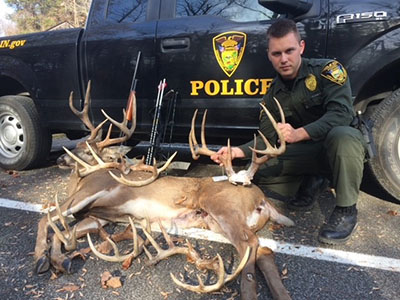 Nathan Lutz with a deer and several sets of antlers