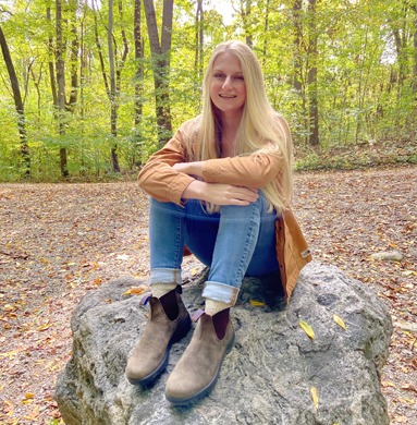 Madison Kresse sitting on a rock in the forest