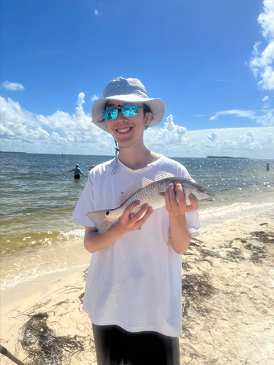 Junior Yang Lui with a red drum he caught hook and line sampling