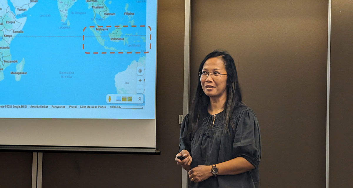 Dr. Christina Mediastika stands next to a map of Asia during a presentation