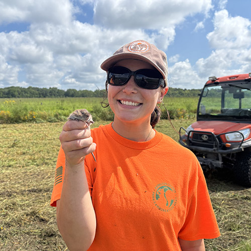 Madi Medley holds a field mouse she found during a break from bush hogging the prairie