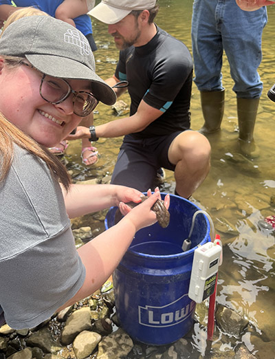 A member of the Indiana Lakes Management Society helps release an eastern hellbender salamander into the wild
