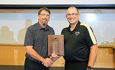 Trent Osmon is presented his 2023 Distinguished Alumnus Award by Dr. Mike Saunders.