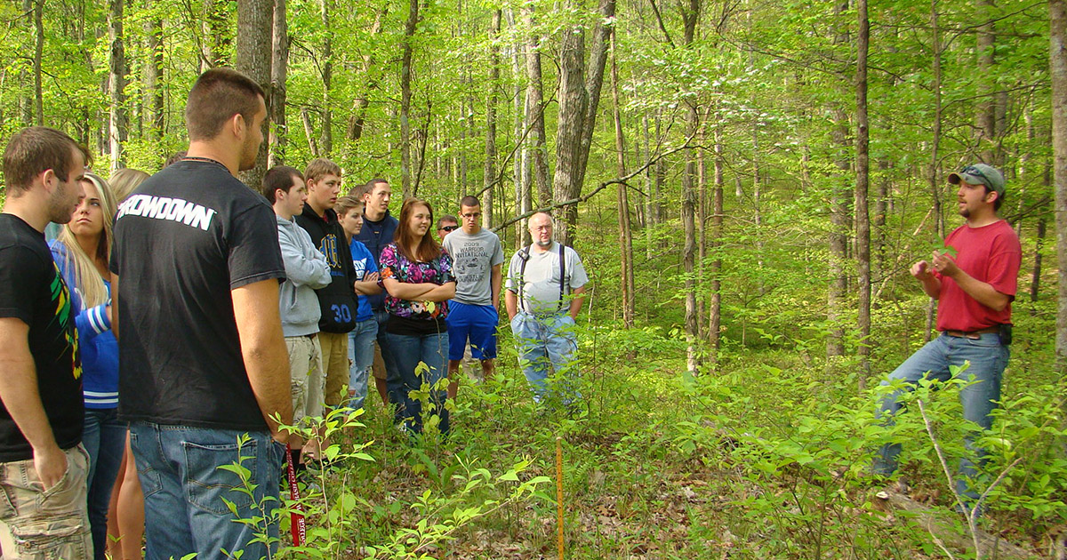 Trent Osmon speaks to a group of students in the forest