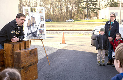 Trent Osmon makes a presentation about the U.S.S. Constitution while leaning on a model of the ship's internal structure