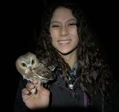 Undergraduate researcher Tabitha Olsen poses with a northern saw-whet owl.