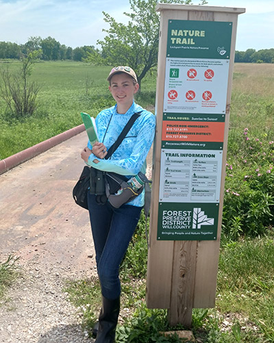 Lydia Pultorak stands next to a nature trail sign