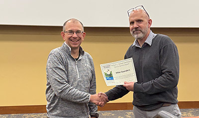 Dr. Mike Saunders receives a certificate for the William L. Hoover Exemplary Faculty Service Award from department head Tomas Höök