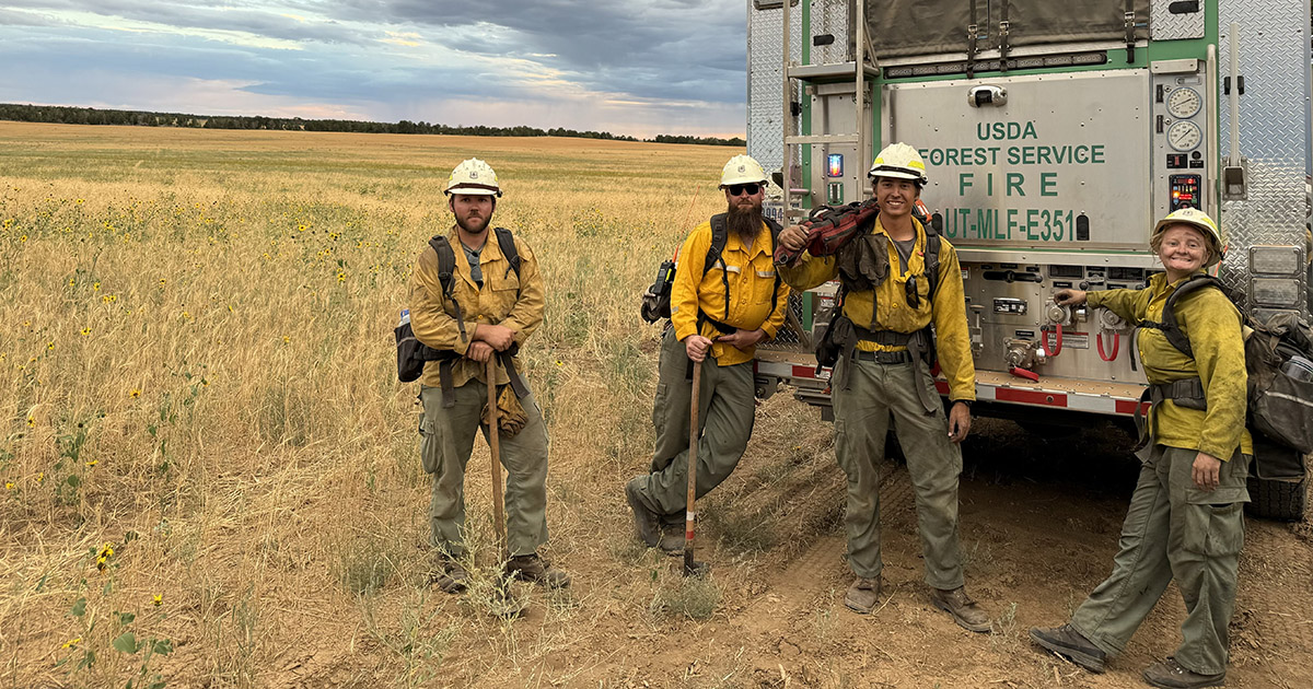 Zane Smoldt stands in front of a fire truck with colleagues from the USDA Forest Service