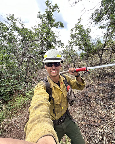 Zane Smoldt holds his firefighting equipment and takes a selfie at his summer job as a forestry technician in Utah