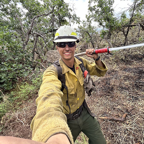 Zane Smoldt stands in front of a fire truck with colleagues from the USDA Forest Service