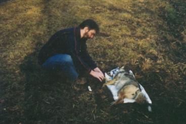 Todd Atwood kneeling next to a coyote