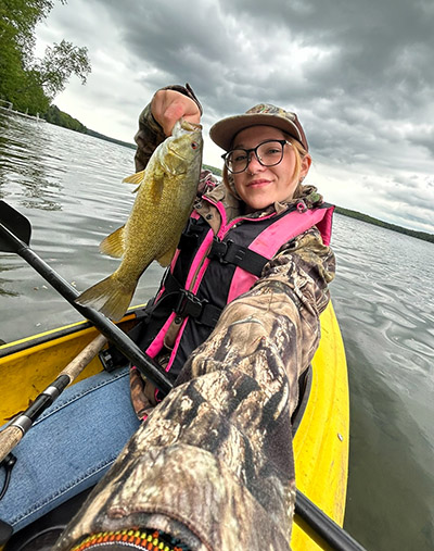 Mallory Wagner takes a selfie with a fish, while fishing in a kayak