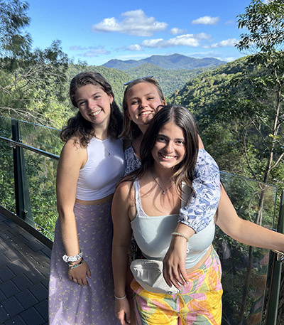 Lauren poses with friends in front of a mountain landscape