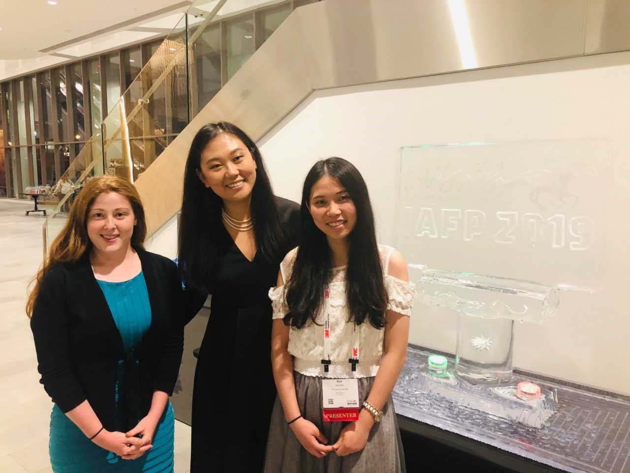  Tressie (right), Dr. Feng (middle), and Han standing in front of the ice sculpture of IAFP 2019