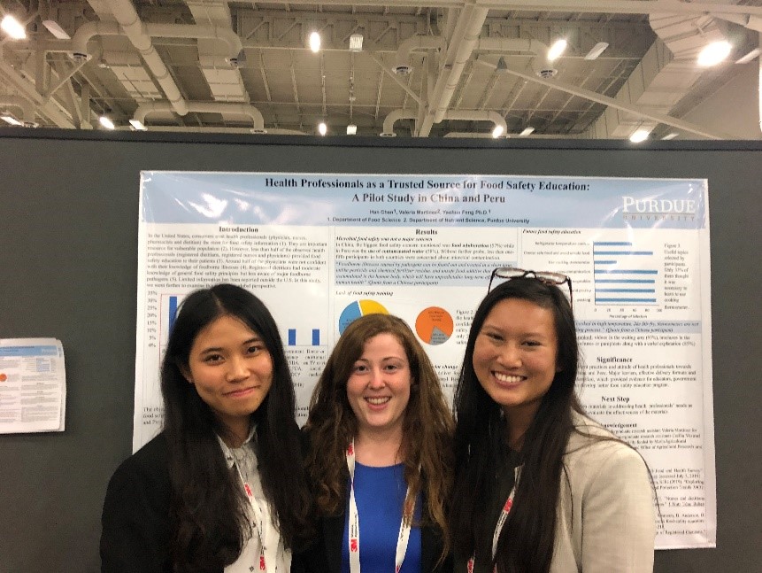 female students presenting a posted in conference