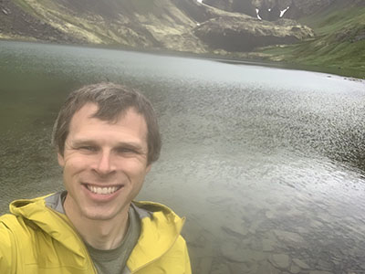 Bill Beatty selfie with mountains, glaciers and a water body behind him