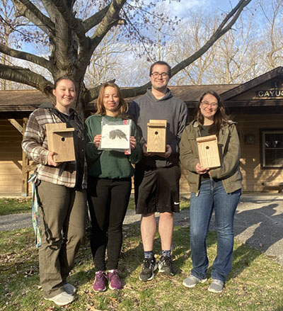 The Missouri Western group of attendees at Conclave show off their creations. Grace, Sonja, and Tyson built birdhouses in the workshop, while Kyla pinned the wing specimen. 