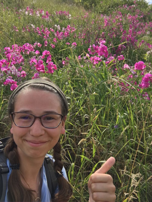 Jessica Elliott in grassland with flowers blooming.