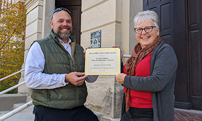 Dr. Rod Williams is presented a certificate by Marilyn Culler of the Hoosier Outdoor Writers group for its 2022 Bayou Bill Conservation Award.