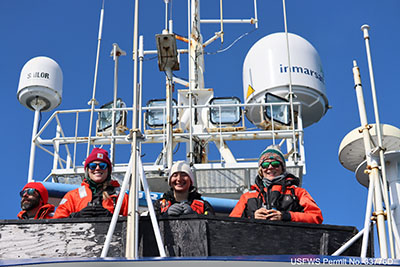 From left:  Joshua Carpenter (USGS volunteer), Ami Everett (USGS biological science technician), Amanda Herbert (USGS biological science technician), and Caroline Cummings (USGS volunteer) conducting Pacific walrus age structure surveys from the RV Norseman II. The team observed walruses hauled-out on sea ice and assigned each animal in a group to an age/sex category according to published criteria. USFWS Permit No. 33776D. 