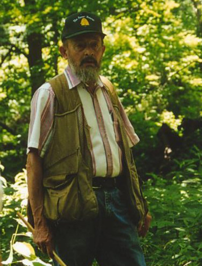 Bob Koenig stands in a wooded area