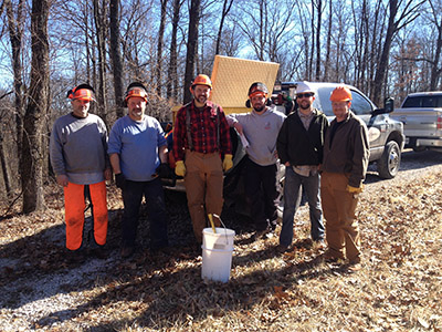 Timber cutters Marty O’Neal and John Maners and timber buyer Jeff Page (FNR 2001) of Tri-State Timber alongside Trent Osmon (FNR 1999), Rhett Steele (FNR 2001) and Brady Miller (FNR 2001, 2003) of the Crane base stand together during the 2014 cutting for the U.S.S. Constitution