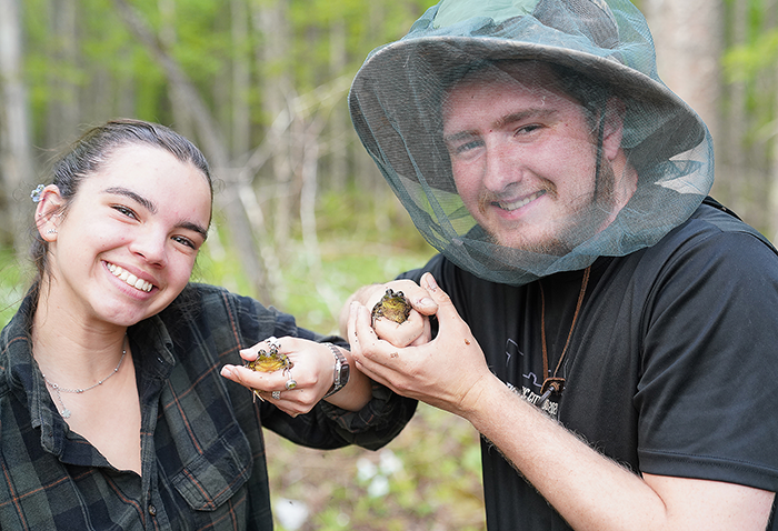 Two FNR students holding frogs found at Summer Practicum.