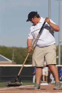 Purdue Baseball grounds crew - student brushing field