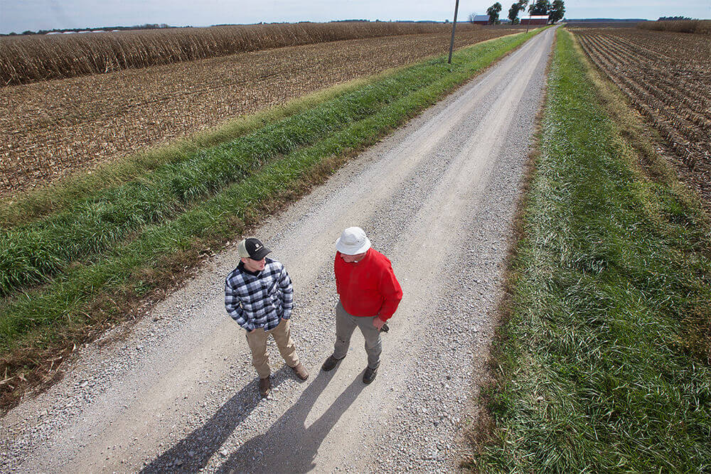 Two men on a road surrounded by farmland