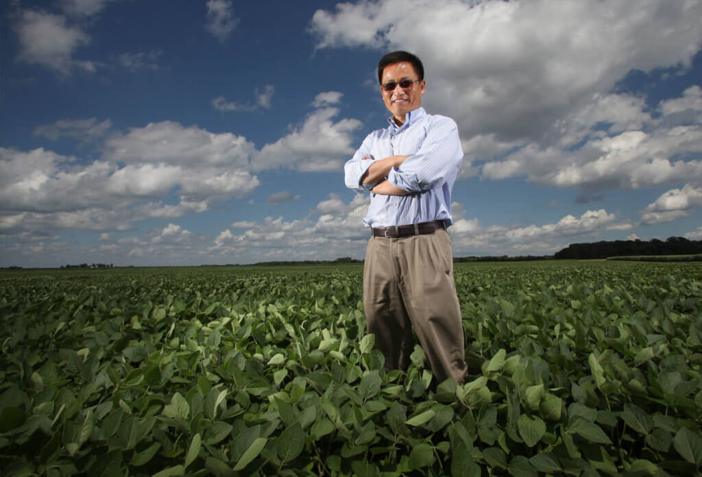 Dr. Jian-Kang Zhu stands in a field with clouds overhead