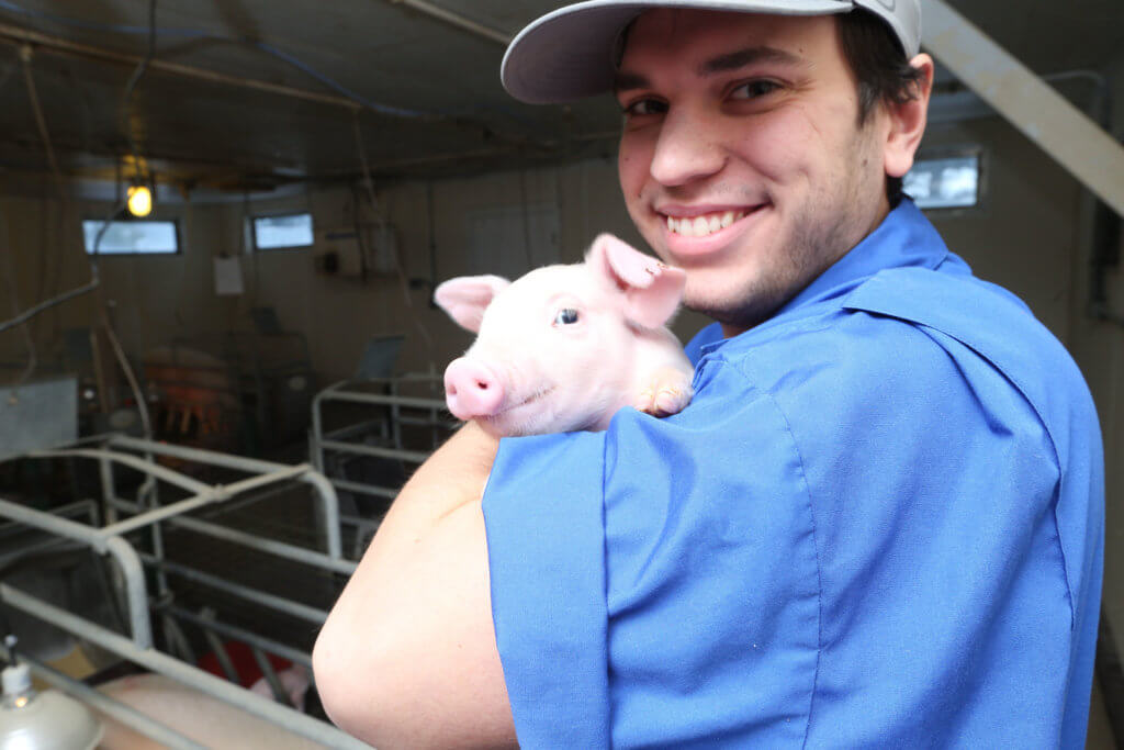 Man holding a piglet and smiling