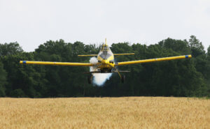 Pilot Tyler Rice flies well below the treeline, preparing to drop a load of soybeans on Kyle Blaydes’ wheat field in Montgomery County.