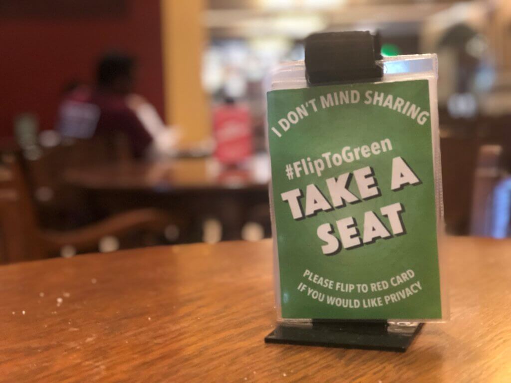 A sign on a table in the union welcoming others to take a seat