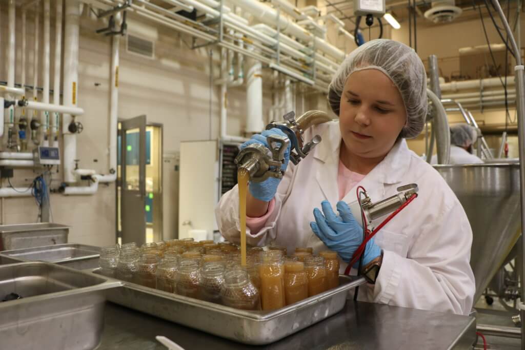 Alyson McGovern, a sophomore in Food Science, works on filling bottles with honey in the Pilot Lab. Photo by Tim Thompson. 