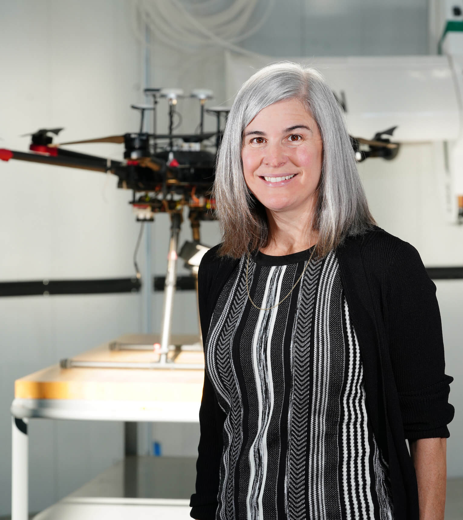 Katy Martin Rainey stands next to unmanned aerial vehicle (UAV) at the Indiana Corn and Soybean Innovation Center.