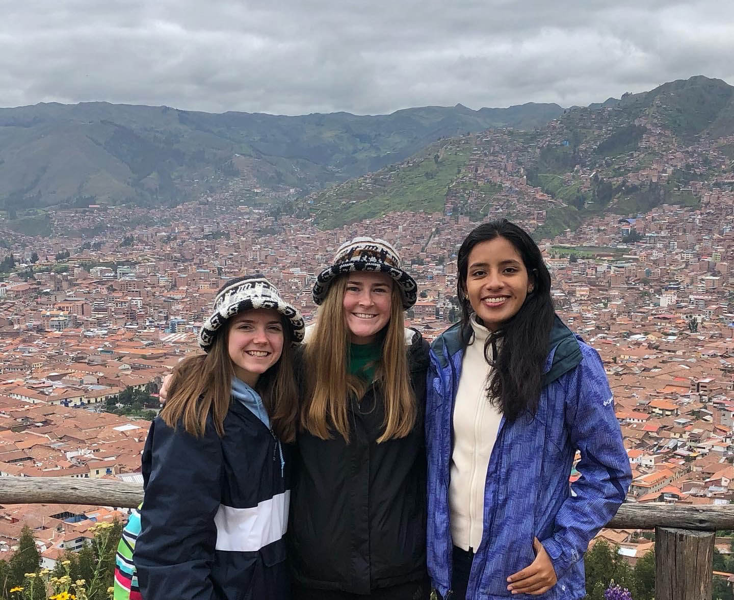 Image of three young women outdoors with the city on the back